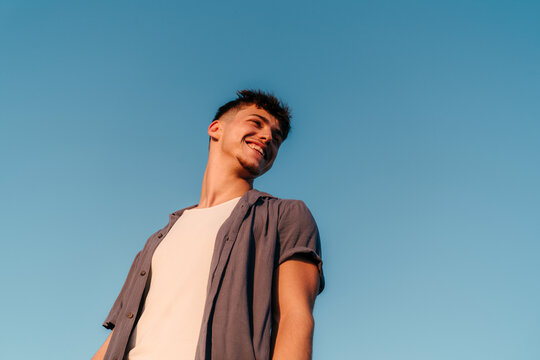 Happy Gen Z man portrait with blue sky