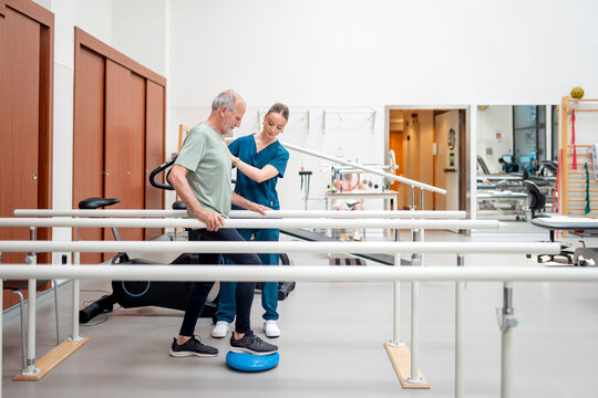 Senior man supported by female therapist during rehabilitation