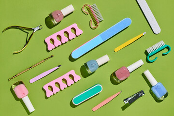 A collection of nail care tools and polish are arranged on a green 