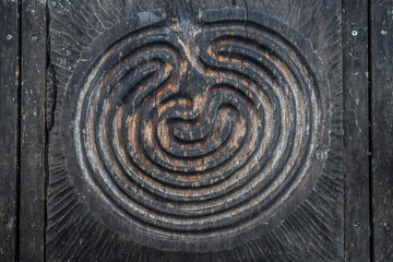 A labyrinth carved into wood, old and textured - horizontal