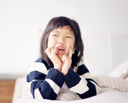 Chinese girl, just woken up, is making a mess and being funny in bed