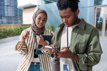 Two young professionals collaborate using a phone and tablet.