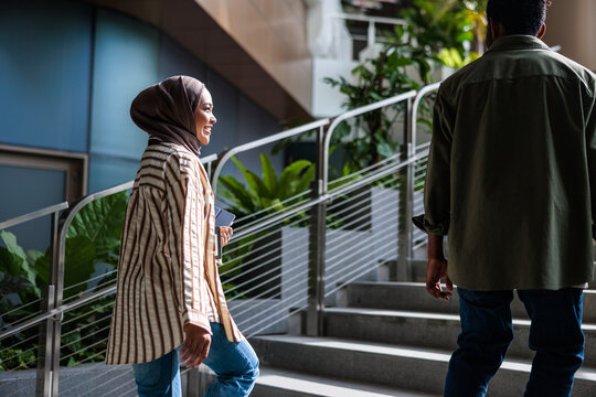 Two people walk up stairs in a modern building.
