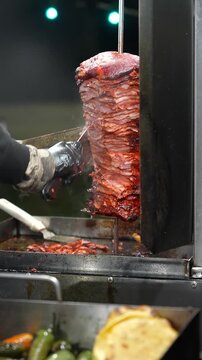 Tender al pastor meat crackles over an open grill in slow motion, sending up waves of steam that suggest smoky spices and the irresistible energy of Mexican street tacosTaco Stand Series - Food vendor