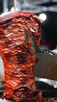Al pastor meat cooks on a grill in slow motion, steam rising to highlight rich flavors and the authentic outdoor street food culture of Mexican tacos - Taco Stand Series - Food vendor