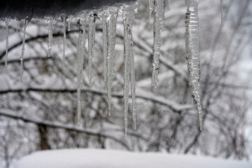 Close-up of long transparent icicles hanging from a roof in winter