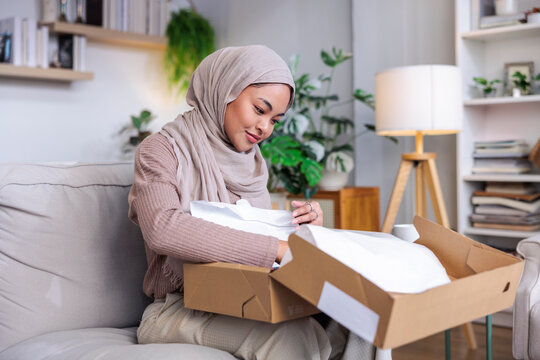 Woman in hijab opens a package at home