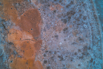 Frozen marshland texture and winding animal trail, winter tundra landscape, cold abstract nature background, aerial drone shot top view