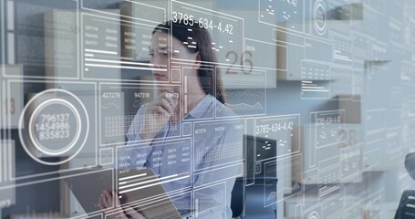 Studying female analyst in blouse interacting with HUD overlays in modern office, holding tablet