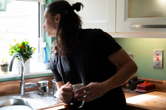 High Contrast Portrait of Person Enjoying Tea by Kitchen Window