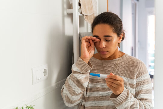 Woman wiping tears while crying after getting pregnancy test results