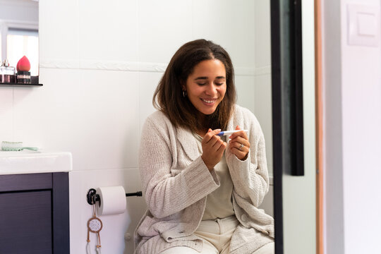 Woman holding pregnancy test and smiling