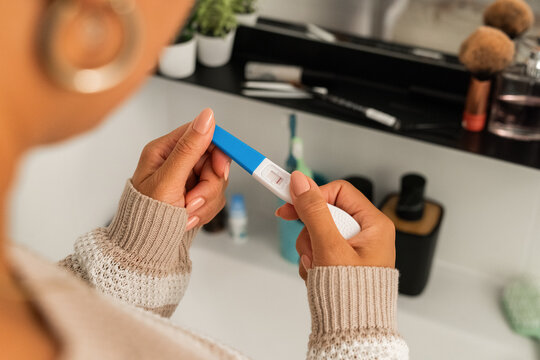 Woman Holding a Pregnancy Test in a Bathroom Setting
