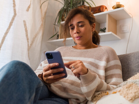 Woman using smartphone at cozy home environment 