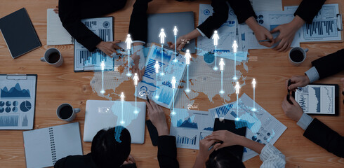A high-angle view of a business meeting showcasing a diverse group analyzing data and presenting strategies with modern technology on a rustic wooden table. Trope