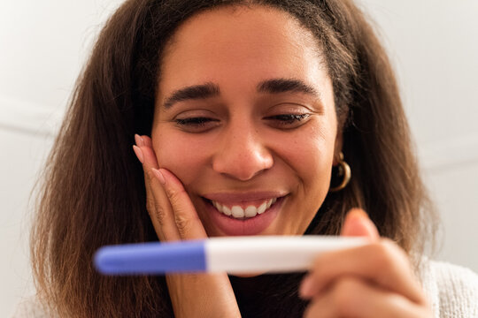 Happy woman crying from happiness seeing positive pregnancy test