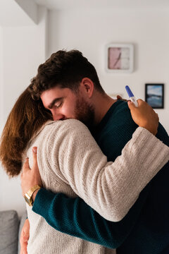 Man hugging his wife celebrating positive pregnancy test
