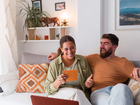 Couple laughing during virtual appointment with specialist at home 