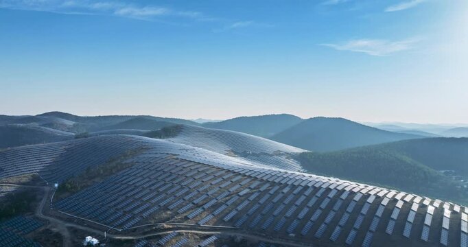 Aerial time-lapse of a solar farm on rolling hills at early morning, showcasing vast rows of photovoltaic panels and serene landscape blending renewable energy with natural terrain.