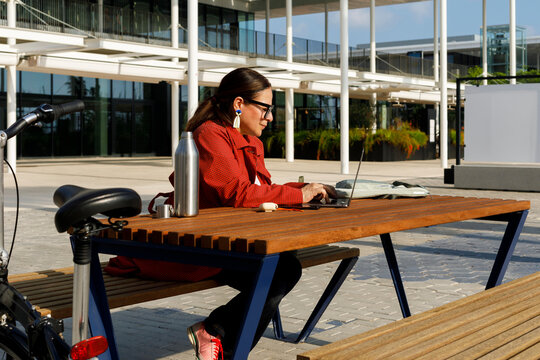 Woman Working on Laptop Outdoors With Bicycle Nearby