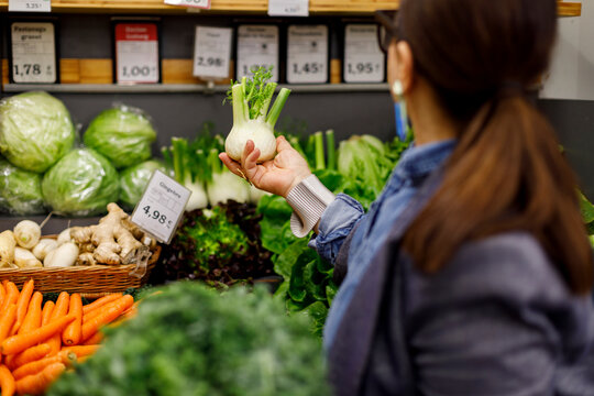 Woman Inspects Fennel At Grocery Store Vegetable Aisle