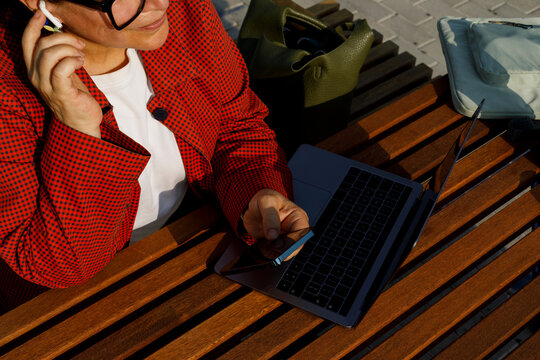Woman Uses Laptop  on Park Bench During Daytime