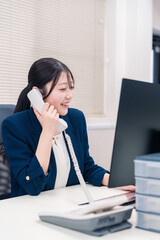 オフィスの固定電話で通話をする女性ビジネスパーソン