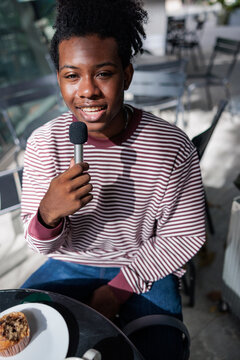 Young man with microphone, striped shirt, and muffin.