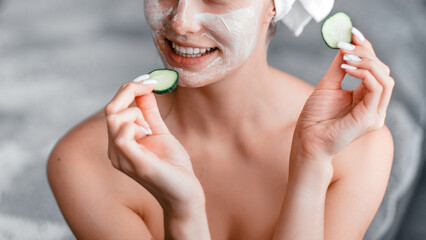 Woman making facial mask holding cucumber slices in her hands. Morning skin care routine. Stay at home while quarantined to avoid coronavirus.