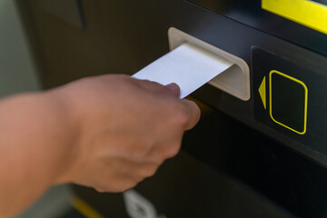 Person Retrieving a Ticket From a Vending Machine in a Public Area