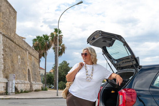 Smiling Woman Standing Near Her Car in y Parking Lot