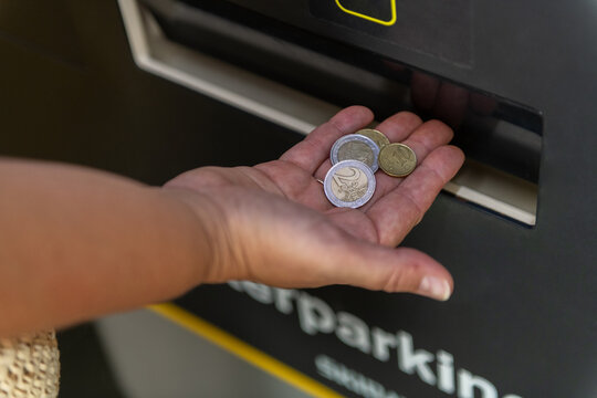 Hand Placing Coins in Parking Meter 