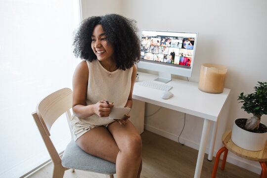 Candid woman smiling at desk with computer and tablet setup in a