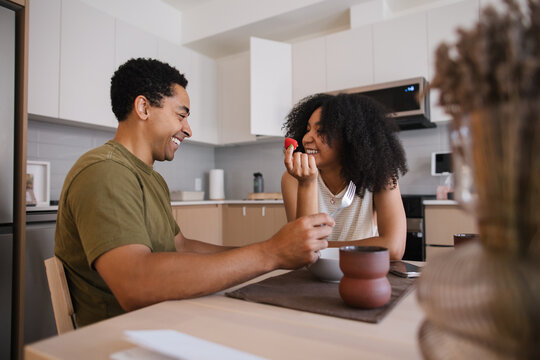 Candid couple sharing a smile during breakfast at home in a mode