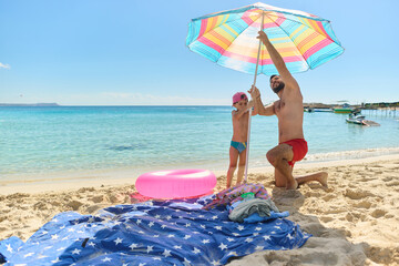 Father and Son Setting Up Beach Umbrella Together