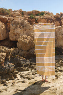 Person Holding a Beach Towel on Rocky Shore