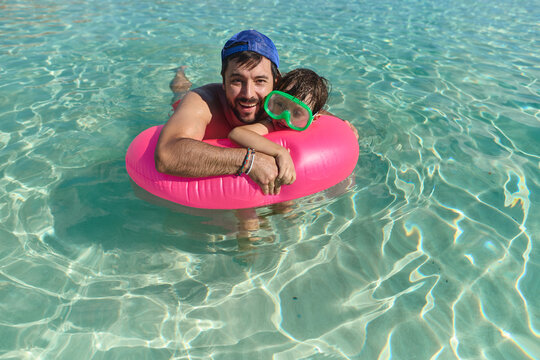 Father and Son Floating Together in Clear Blue Sea