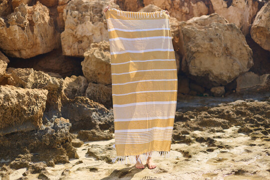Person Holding a Beach Towel on Rocky Shore