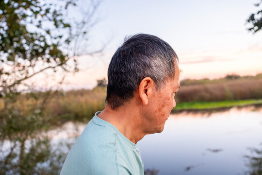Senior Man Reflecting by a Peaceful Lakeside at Sunset