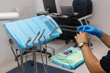Dentist wearing medical gloves prepares dental equipment and instruments in a modern dental clinic....