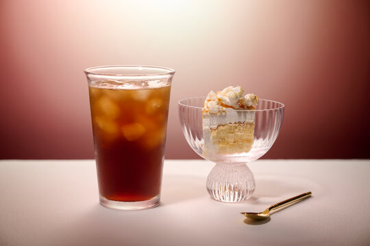 Refreshing iced tea and cake slice with whipped cream in a glass bowl