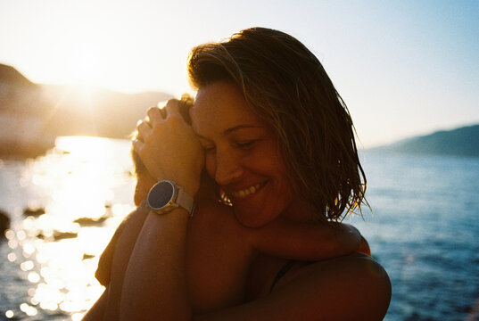 Mother cuddles her daughter at the seashore