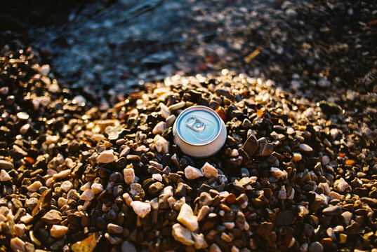 Beer can hidden in pebbles