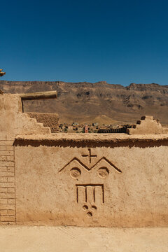Berber Symbol Carved in Kasbah Wall with Mountains on Background