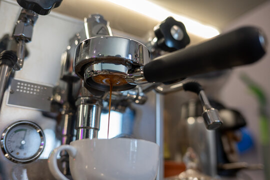 Making espresso with a naked filter into a white cup.