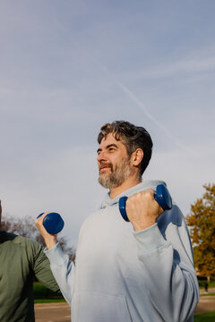 Elderly man performing weight exercises to maintain strength