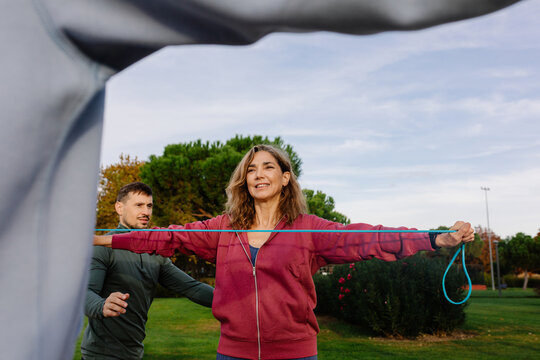 Personal trainer instructs active elderly woman in strength exercises