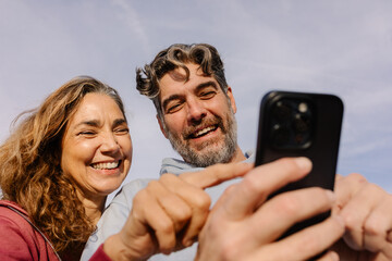 Senior couple sharing a cheerful moment while looking at a smartphone