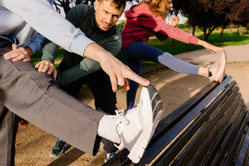 Personal trainer assists an elderly couple during a stretching routine