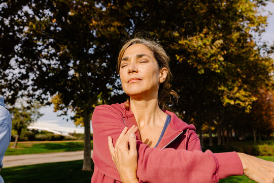 Middle-aged woman performing arm stretching exercises